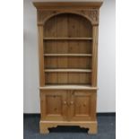 A set of carved pine open bookshelves fitted double door cupboards beneath,