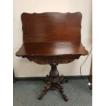 An Edwardian mahogany carved tea table on pedestal support