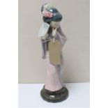 A Lladro figure of a geisha hiding behind fan