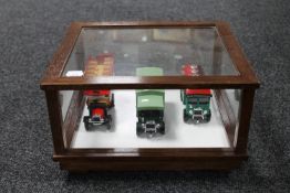 Three die cast vehicles in a glass and wood counter display cabinet