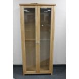 A double door contemporary beech display cabinet with glass shelves