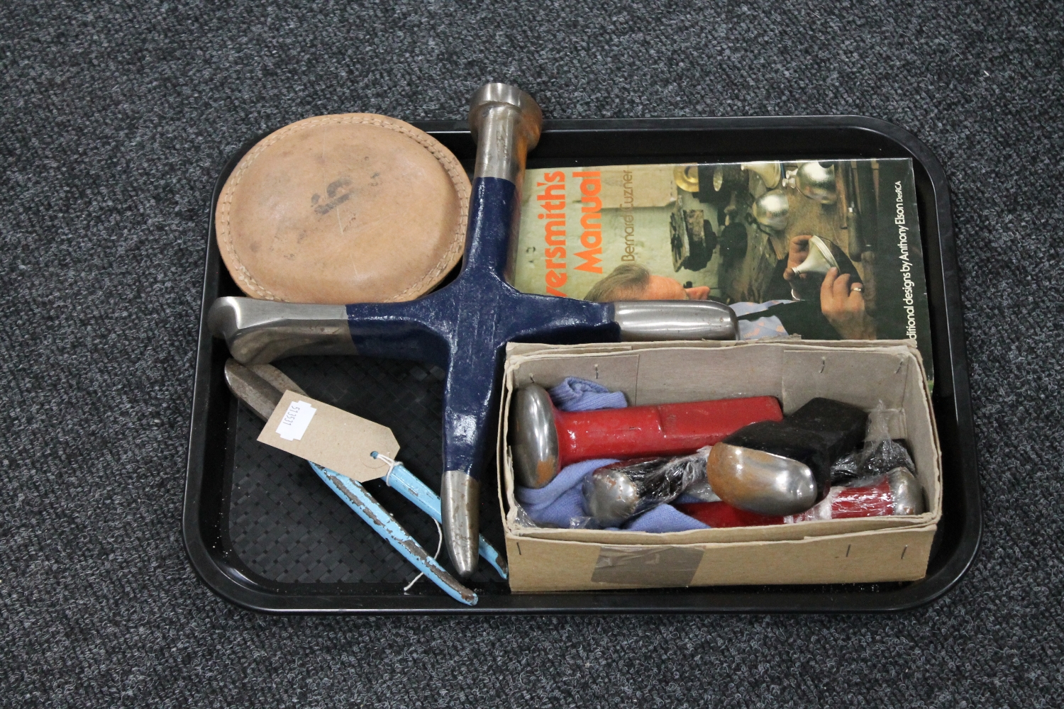 A tray containing silver-smithing tools together with a related book