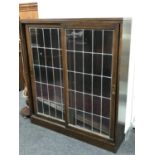 An oak double door sliding leaded glass door bookcase