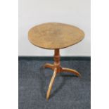 A circular tilt top pedestal occasional table