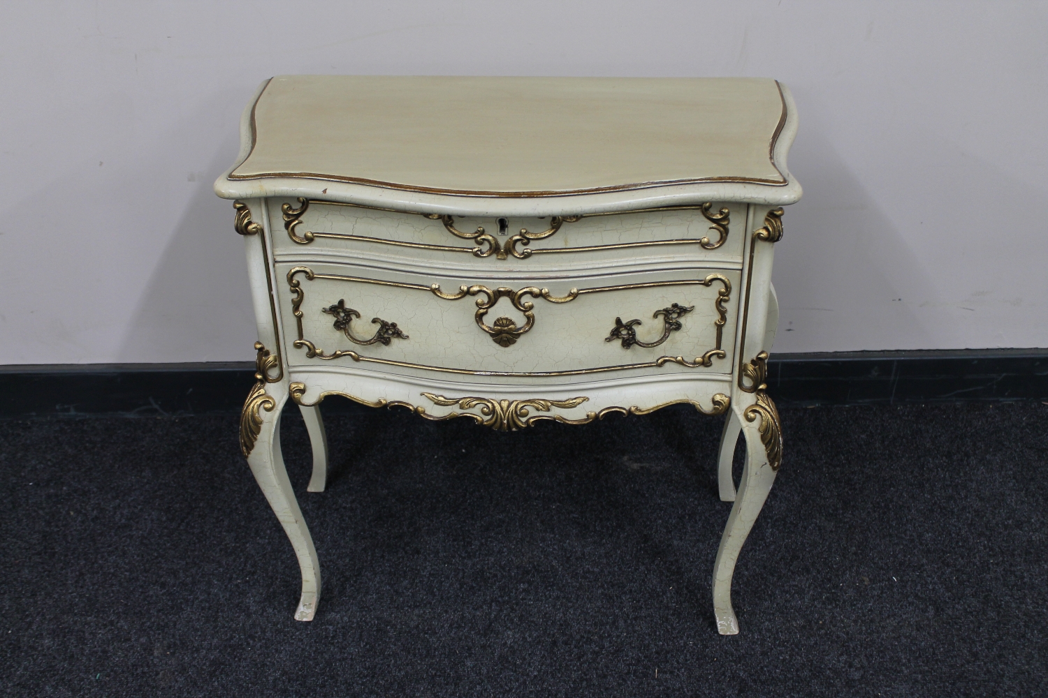 A French cream and gilt two drawer chest on cabriole legs