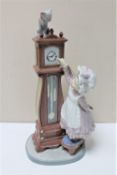 A Lladro figure of a girl and a grandfather clock