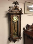 A Victorian walnut eight day wall clock with enamelled dial and carved eagle pediment