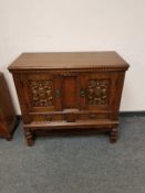 A carved oak double door low cupboard,