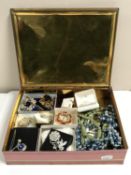 A vintage tin of assorted costume jewellery including brooches, necklaces,