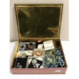 A vintage tin of assorted costume jewellery including brooches, necklaces,