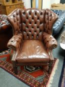 A brown leather buttoned Chesterfield wing backed chair, width 94 cm.