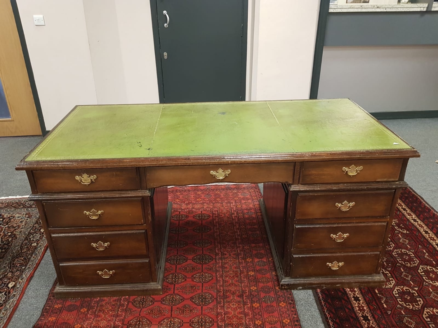 An oak twin pedestal desk with green tooled leather top,