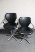 A pair of black vinyl and metal hydraulic barber's chairs
