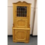 A blond oak corner cabinet with stained leaded glass panel