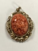 A 9ct gold mounted coral pendant, 7g. CONDITION REPORT: 39mm by 25mm overall.