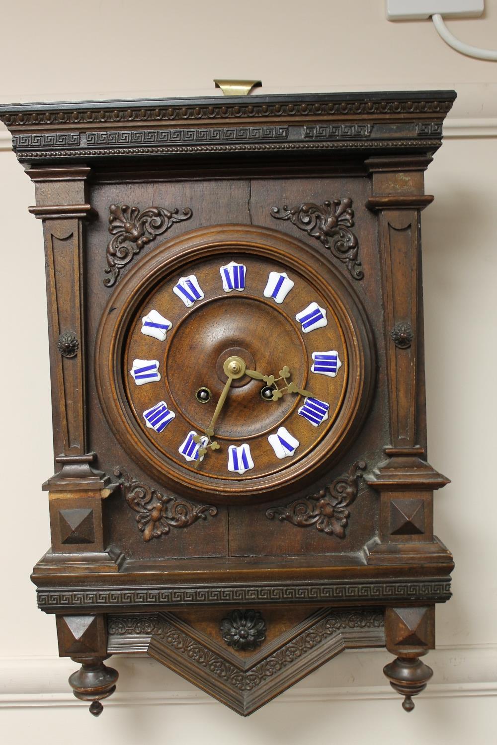 A continental carved wall clock with enamelled numbers