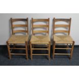 A set of three pine ladder back rush seated kitchen chairs