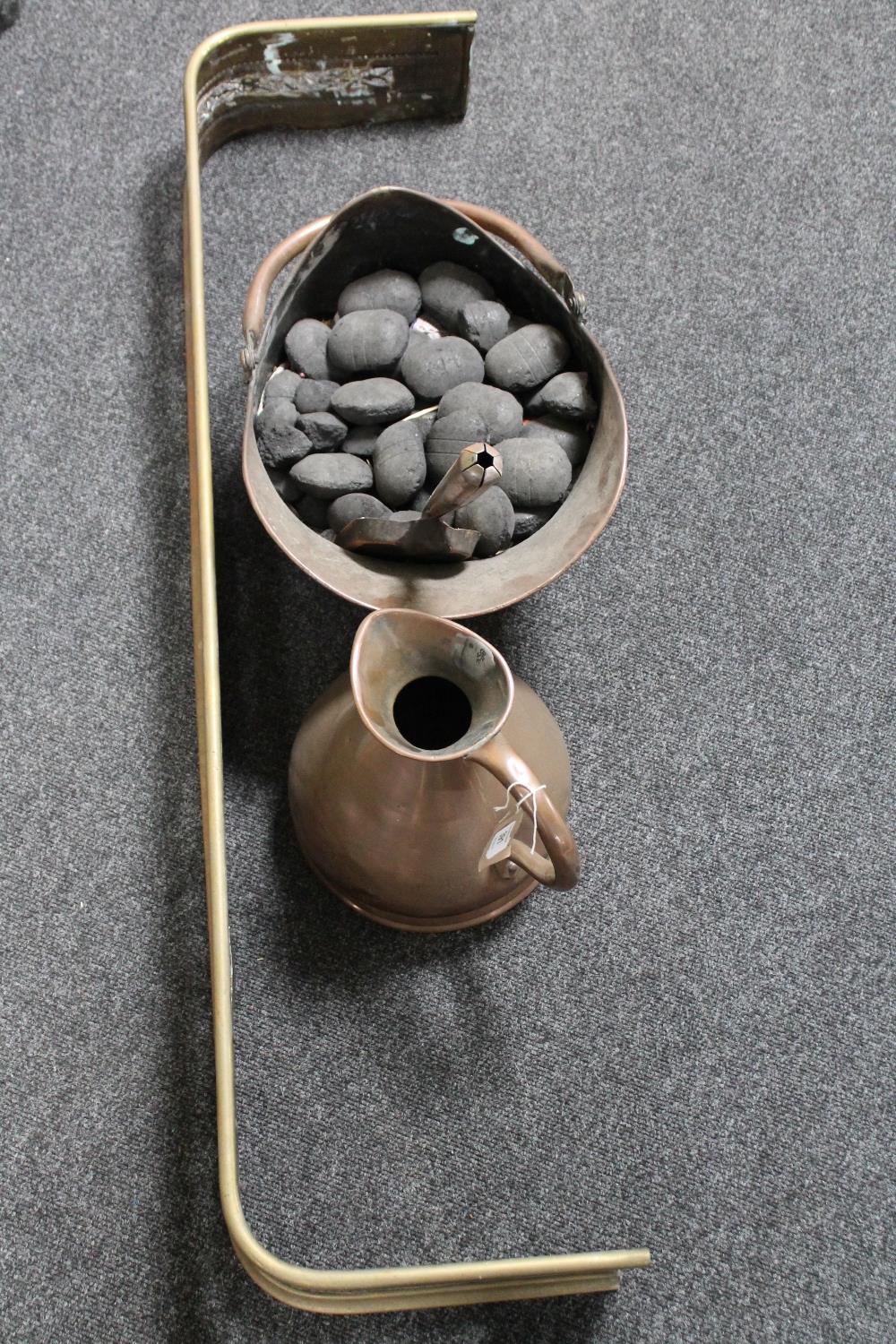 An antique copper coal bucket with shovel together with measuring jug and brass fire curb