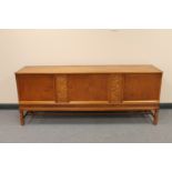 A stained beech triple door sideboard with two carved panels