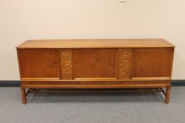 A stained beech triple door sideboard with two carved panels