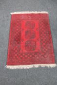 A fringed Persian rug on red ground