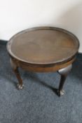 A circular walnut coffee table on claw and ball feet