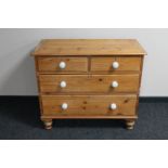 An antique pine four drawer chest with white porcelain handles