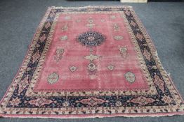 A Persian rug of geometric design on pink ground,