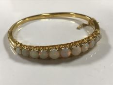 A fine 14ct gold graduated opal bangle, 21.2g, width internally approximately 60mm x 48 mm.