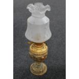 A continental brass embossed oil lamp with glass shade and chimney