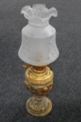 A continental brass embossed oil lamp with glass shade and chimney