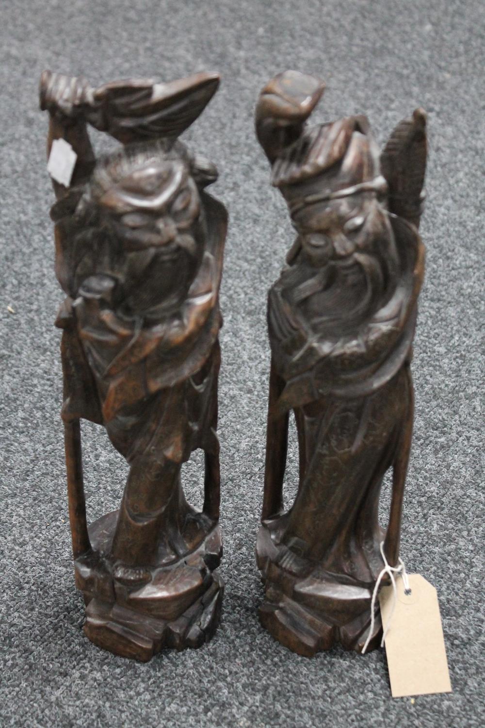 A pair of Oriental intricately carved wooden figures modelled as two village elders,