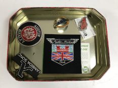 A tin of London Transport badge number 452, two Austin Healey sew on patches,