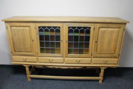 A blonde oak four door sideboard with leaded glass doors