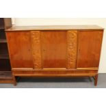 A stained beech triple door sideboard with two carved panels with three drawers beneath