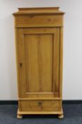 An early 20th century pine pillar cabinet fitted a drawer