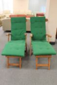 A pair of teak steamer garden armchairs with footrests and cushions