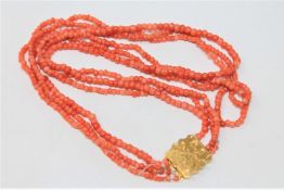 An antique triple strand coral necklace with high carat gold clasp