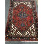 A fringed Persian rug of geometric design on red ground