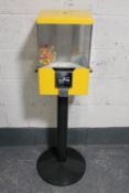 A gumball dispenser on metal stand