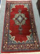 A fringed Persian rug of geometric design on red ground