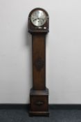 An early 20th century oak granddaughter clock with silvered dial