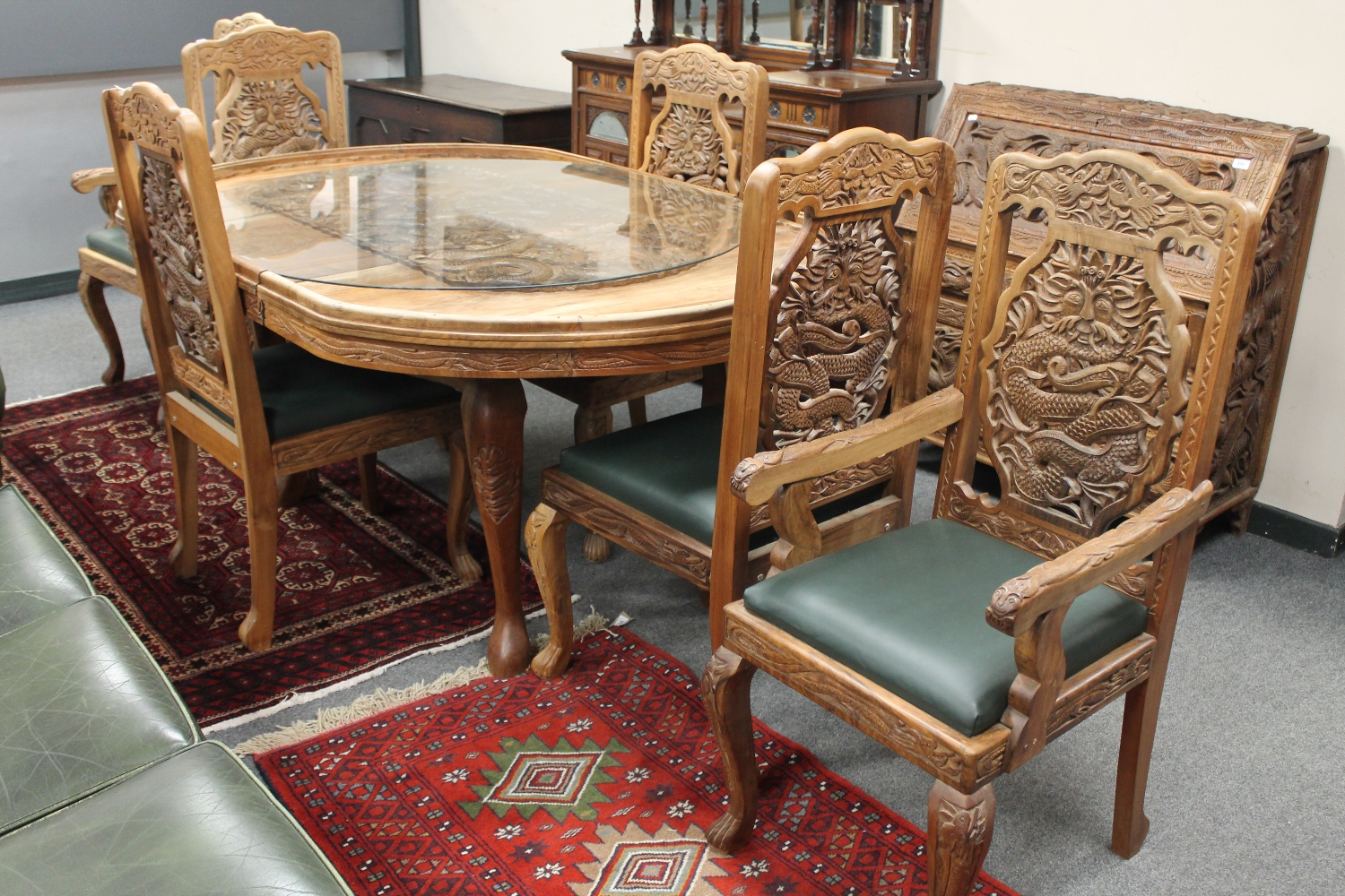 A profusely carved hardwood Indian extending dining table, together with six chairs,