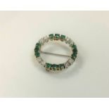 An 18ct gold diamond and emerald circular brooch, approximately 1.5ct, 5.2g.