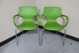 A pair of Armet Sofia green plastic armchairs on metal legs