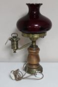 A continental wood and brass oil lamp with chimney and red glass shade (wired)