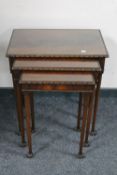 A nest of three mahogany glass topped tables on claw and ball feet