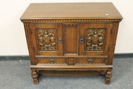 A carved oak low cabinet fitted with two drawers,