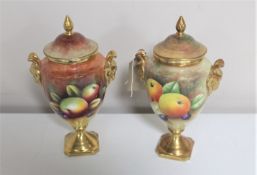 Two Coalport gilded lidded urns painted with panels of fruit by Neil Higgins and Anthony Baggott,