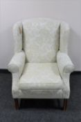 A wingback armchair upholstered in a cream floral fabric